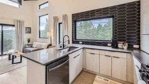 A modern kitchen with a large window, a built-in island, and a view of the outdoors.