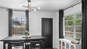 A dining area with a black table and chairs, a pendant light, a window with blinds, and a white radiator with a plant on it. - The Oak on 6th Walk to the Historic Square (Georgetown)