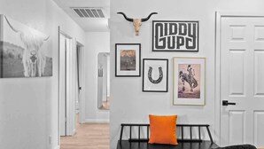 A hallway with a black bench, a skull decoration, and framed pictures on the wall. - The Oak on 6th Walk to the Historic Square (Georgetown)