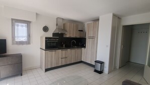 Eine moderne Küche mit Holzausstattung, einer schwarzen Arbeitsplatte, einem eingebauten Backofen und einem Fernseher auf einem grauen Schrank.
