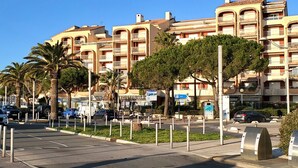 Ein mehrstöckiges Hotel mit Balkonen, einem Parkplatz und Palmen.