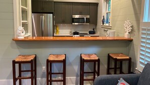 A kitchen with a central island, bar stools, and a seating area with a sofa. - "Nauti-Jayne" coastal cottage in Historic Old Town Bluffton (Bluffton)