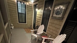 A covered porch with two Adirondack chairs, a small rug, and a decorative anchor. - "Nauti-Jayne" coastal cottage in Historic Old Town Bluffton (Bluffton)