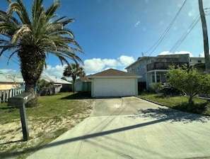 A residential area with a single-story house, a garage, and a palm tree.
