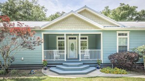 A two-story house with a front porch, a small garden, and a mailbox. - 4br House-Backyard -Pet-friendly-Bay Acess -W-fi (Gulf Shores)