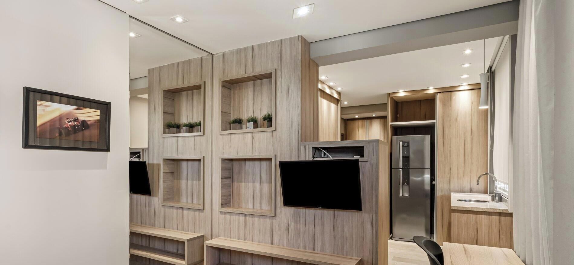 A modern kitchen with built-in appliances, wooden cabinetry, and a flat-screen TV.