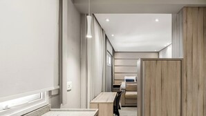 Un pasillo con un armario de madera, un banco y vistas a una habitación con cama y ventana.