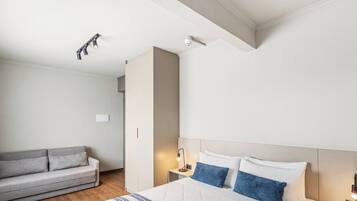 A hotel room with a bed, a sofa, a nightstand, and a ceiling light fixture.
