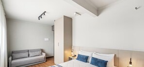 A hotel room with a bed, a sofa, a nightstand, and a ceiling light fixture. - Edifício Congonhas Aeroporto (São Paulo)