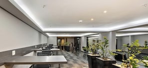 Un hall d’hôtel moderne avec un long comptoir d’accueil, un espace salon et des plantes en pot.