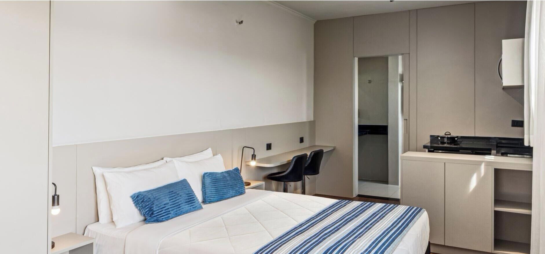 Une chambre d’hôtel avec un lit, un bureau et une kitchenette.