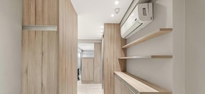 Un couloir aux murs recouverts de lambris en bois, avec un plafond blanc et un appareil de climatisation fixé au mur.