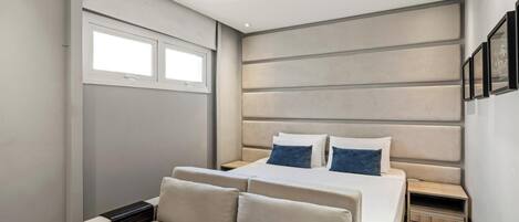 A modern bedroom with a large bed, two bedside tables, and a window.