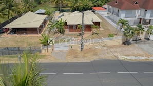 A residential area with houses, a paved road, and a fenced yard. - Villa Exotique (Le Moule)