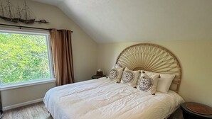A bedroom with a large bed, a window with curtains, a wooden floor, and a ship decoration on the ceiling. - Bright Boho Walkable House Bars Beaches Bike Path Downtown (Muskegon)