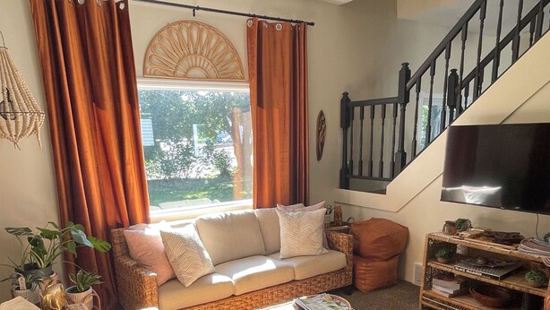 A cozy living room with a sofa, a coffee table, and a TV stand. - Bright Boho Walkable House Bars Beaches Bike Path Downtown (Muskegon)