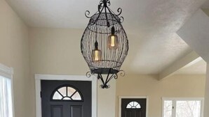 A dining area with a round table, black chairs, and a black chandelier. - Bright Boho Walkable House Bars Beaches Bike Path Downtown (Muskegon)