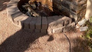 A stone waterfall feature with a circular stone basin at its base. - Garden Patio Home in Chandler, AZ (Chandler)