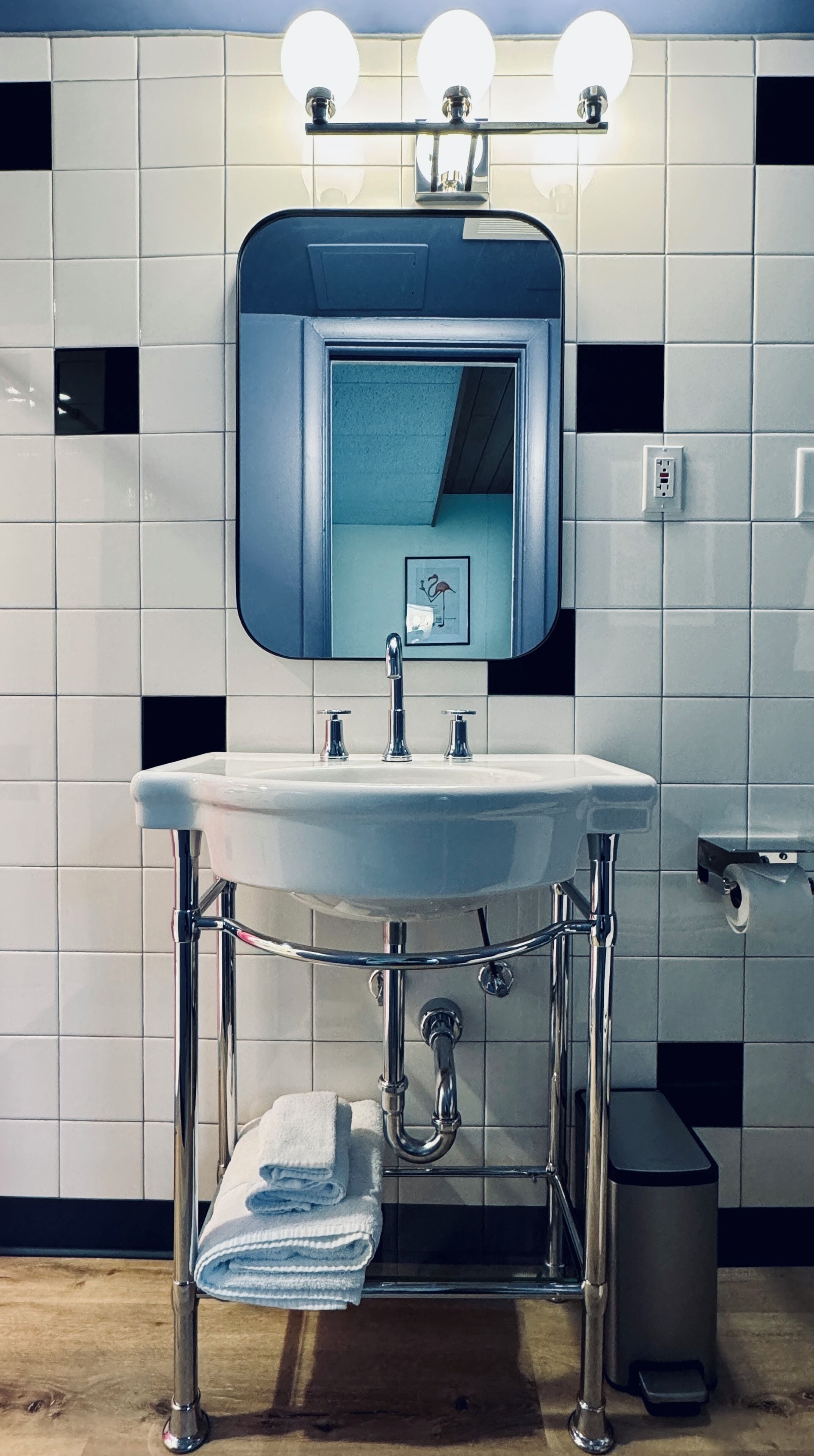 Ein Badezimmer mit einem weißen Waschbecken, chromfarbenen Armaturen und einem Spiegel darüber.
