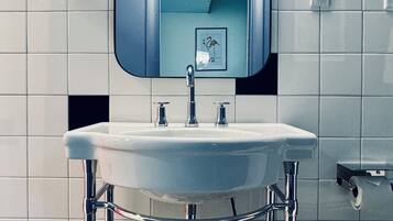 Ein Badezimmer mit einem weißen Waschbecken, chromfarbenen Armaturen und einem Spiegel darüber.