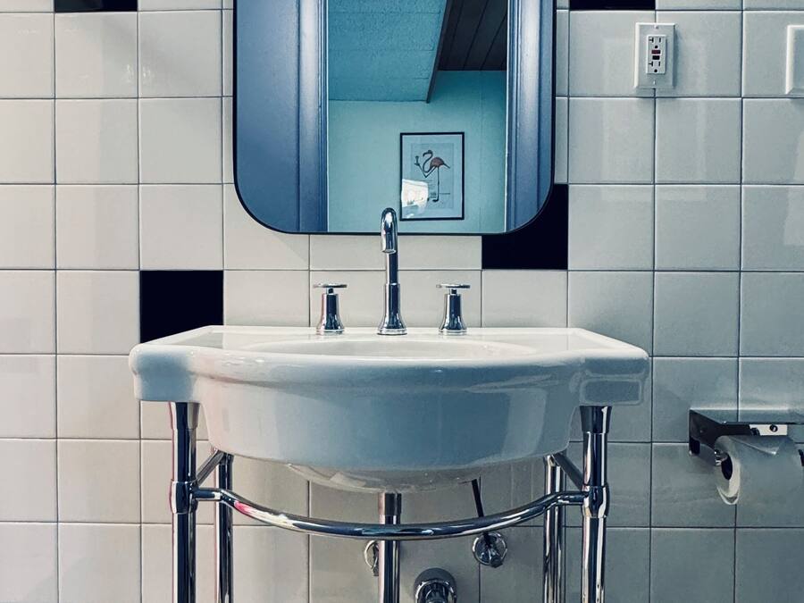 A bathroom with a white sink, chrome fixtures, and a mirror above it.