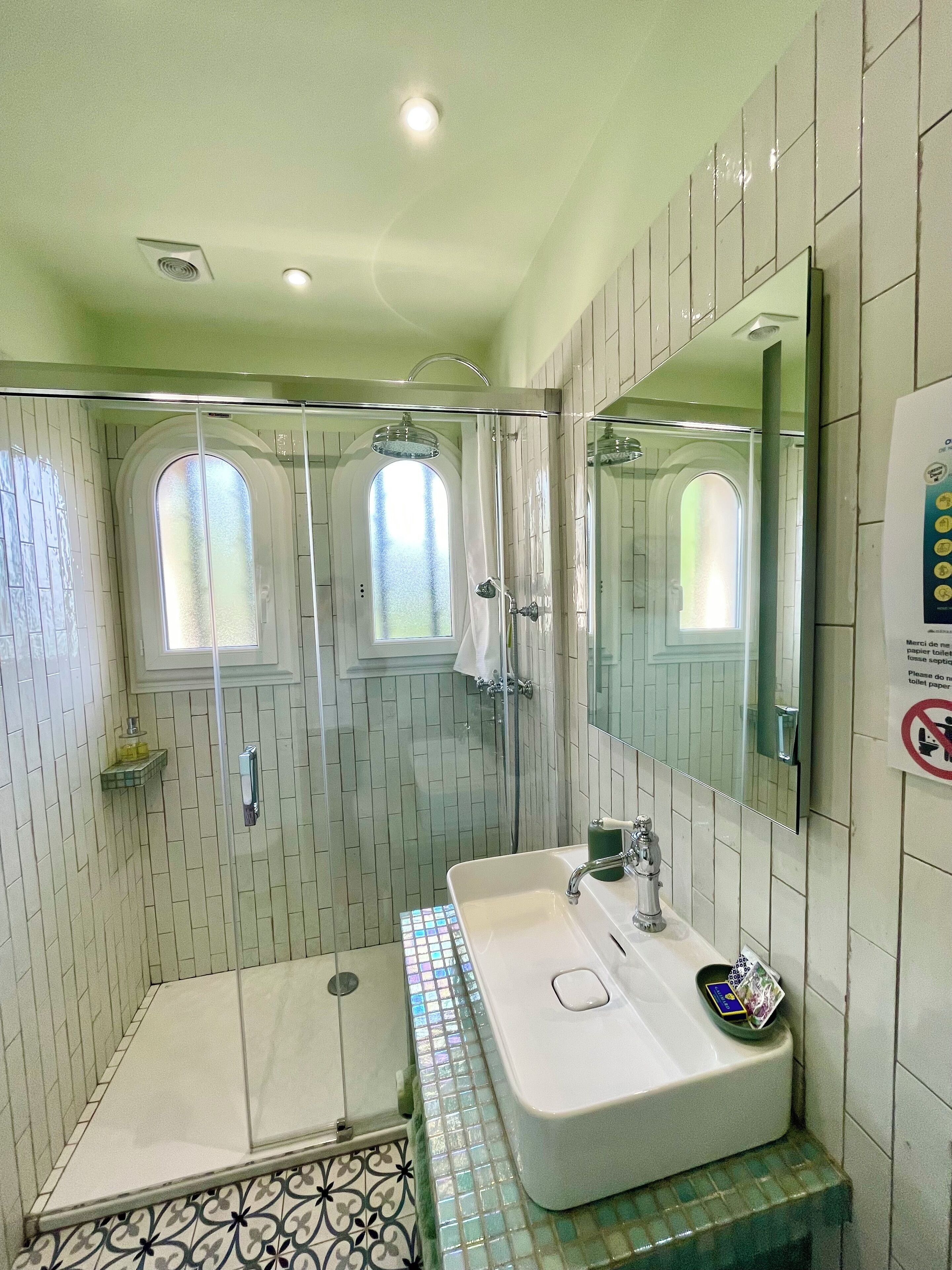 A bathroom with a shower, a sink, and a mirror.