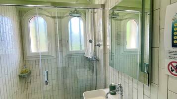 Un baño con ducha, lavamanos y espejo.