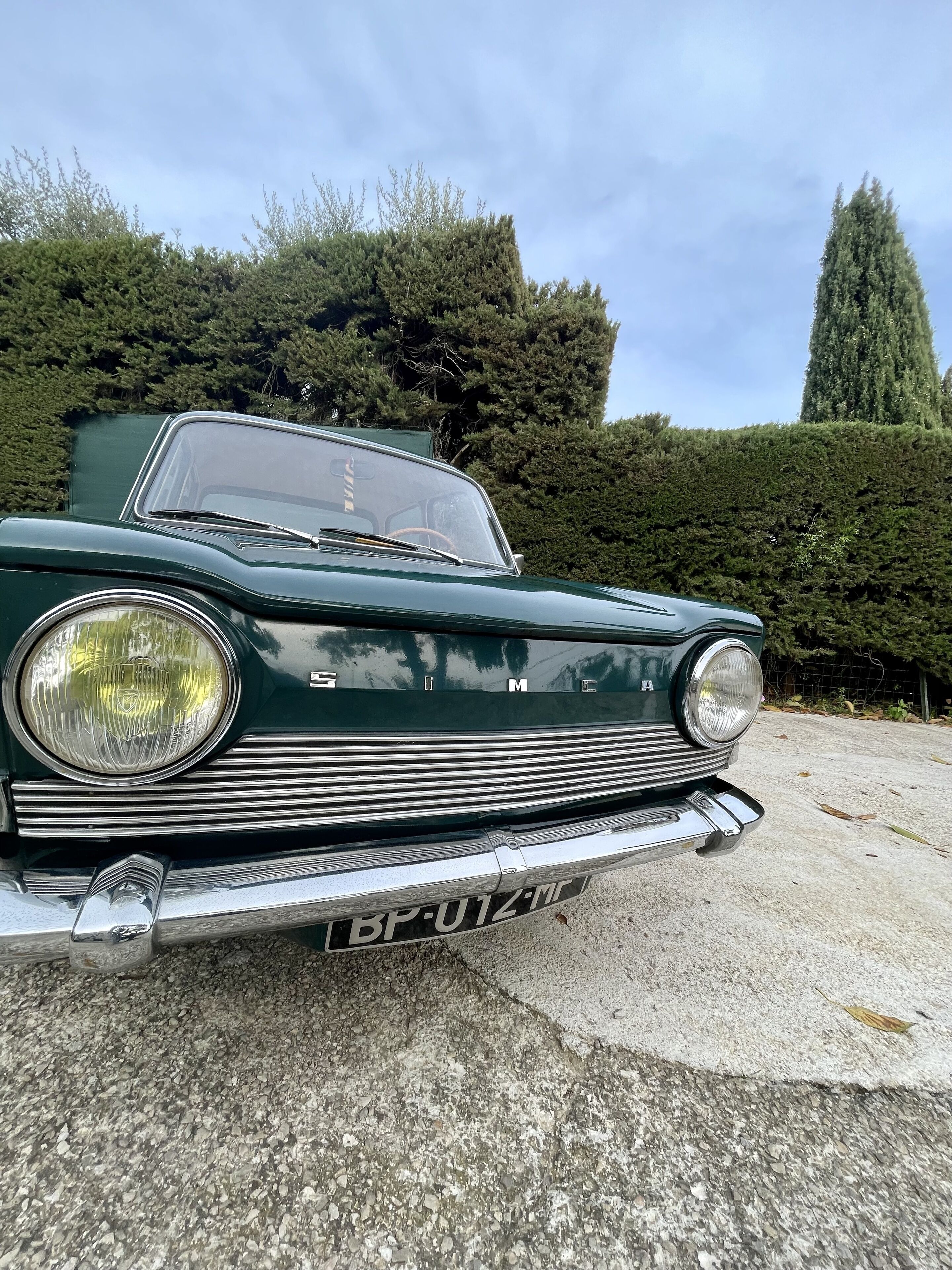 Un coche verde antiguo estacionado sobre una superficie de hormigón con una placa de matrícula.
