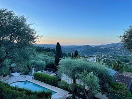 Una piscina rodeada de exuberante vegetación y vistas a un pueblo lejano.