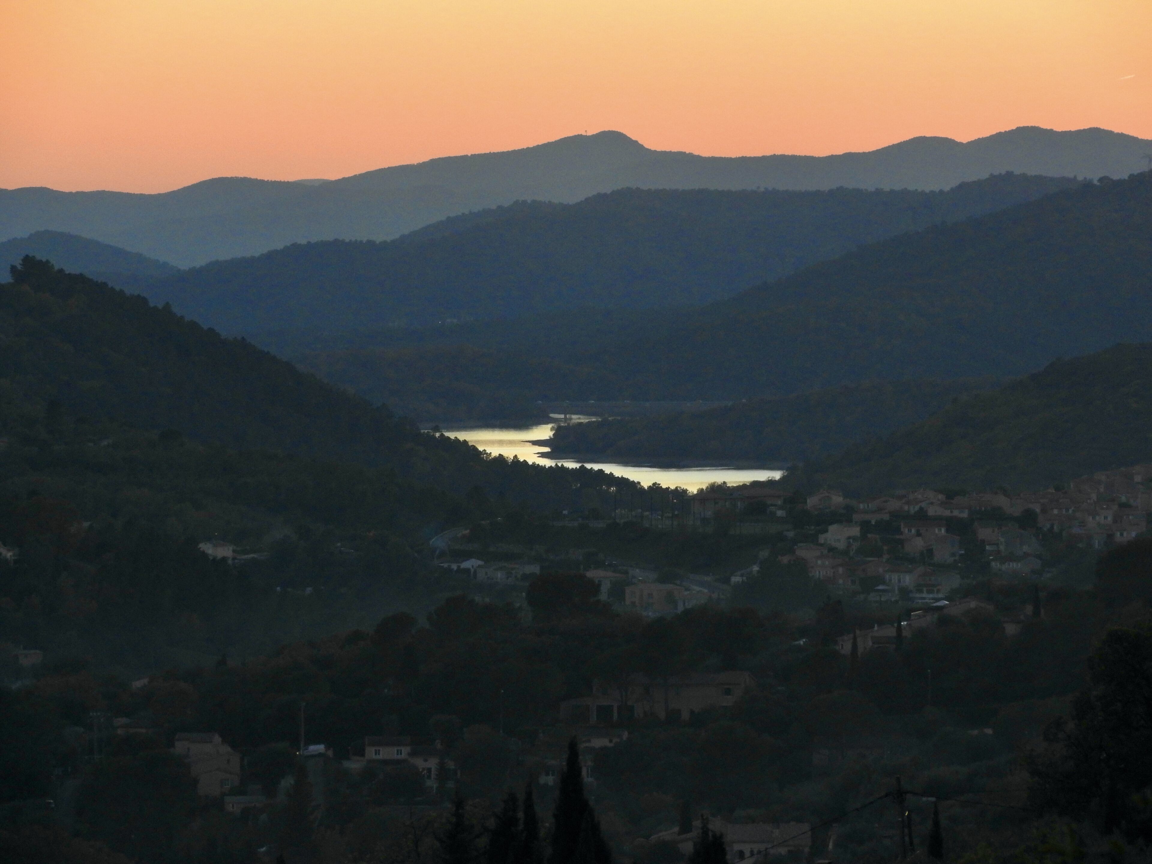 A valley with a river, surrounded by hills and a small town.