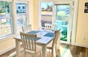 Un área de comedor con una mesa, sillas, una ventana y una puerta que da al exterior.