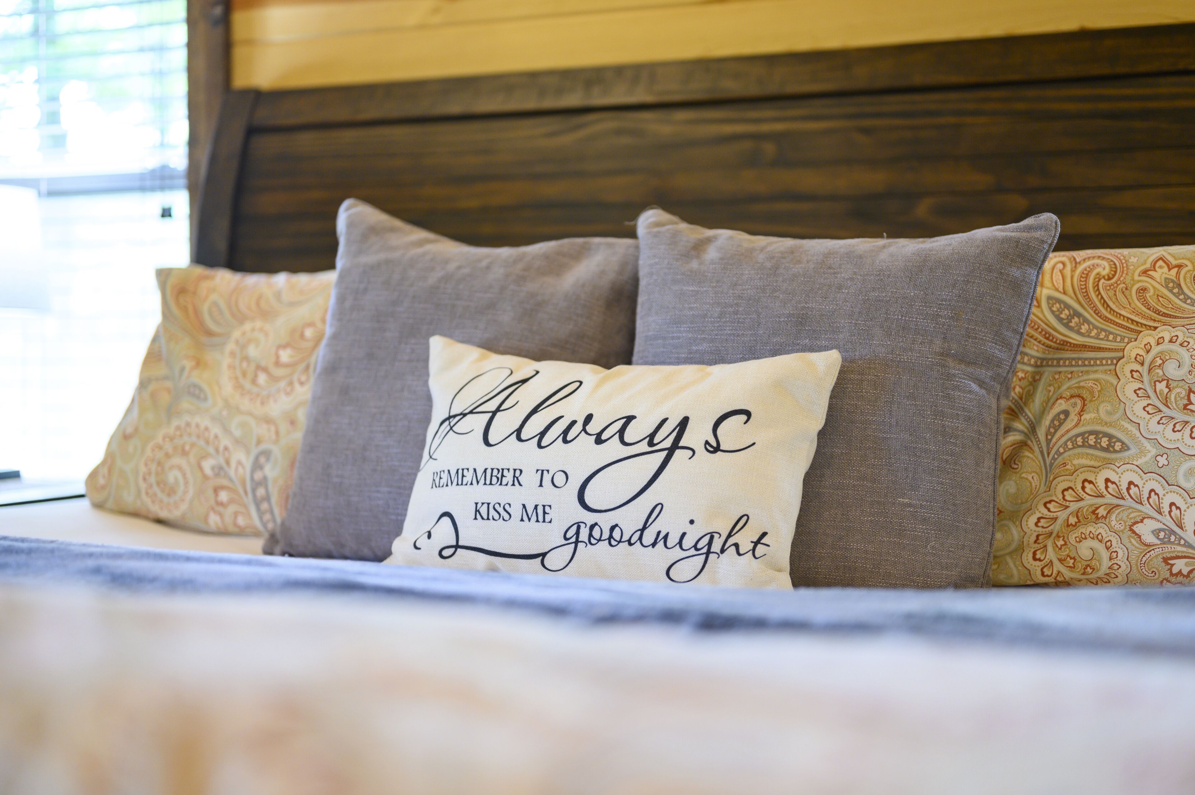 A bed with three pillows, one with a message.