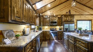 A spacious kitchen with wooden cabinets, stainless steel appliances, and a marble countertop.