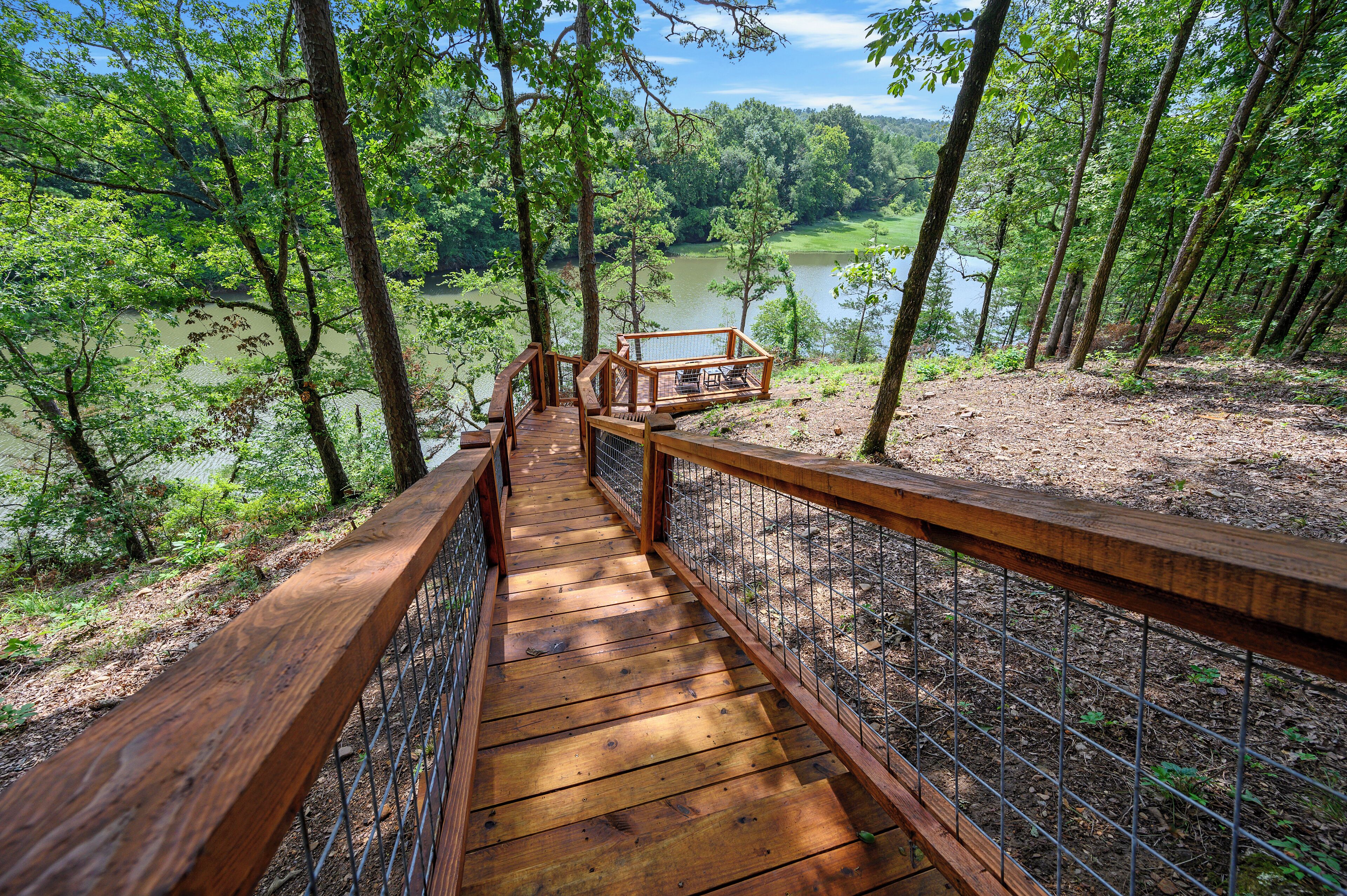 A wooden deck with a metal railing overlooking a lake surrounded by trees.