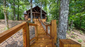 A wooden staircase leading to a cabin in a forest.