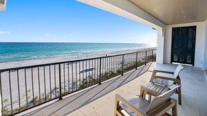 A balcony with a view of the beach and ocean.