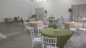 A conference room with round tables and white chairs, equipped with speakers and potted plants. - Hotel Metropolitano  (Major Vieira)