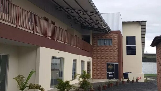 A building with a flat roof, a balcony with vertical railings, and a sign indicating a hotel entrance. - Hotel Metropolitano  (Major Vieira)