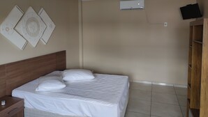 A bedroom with a bed, a nightstand, a wall-mounted air conditioner, and a television on the wall. - Hotel Metropolitano  (Major Vieira)