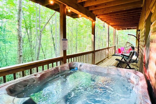A hot tub on a wooden deck with a view of a forest.