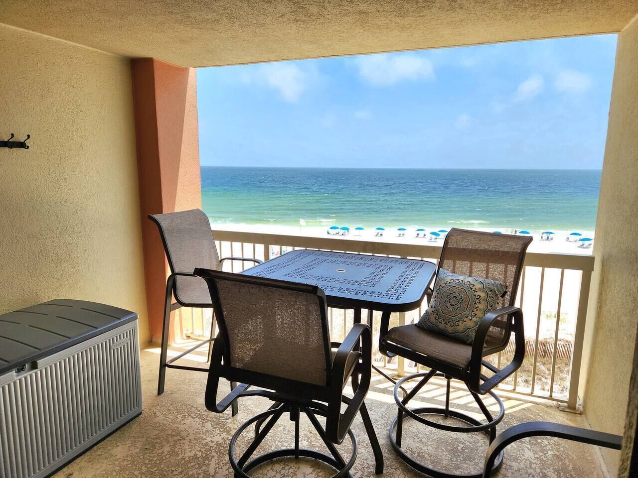 A balcony with a table and chairs, a radiator, and a view of the beach.