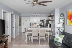 A modern kitchen with white cabinets, stainless steel appliances, and a dining area with a table and chairs.