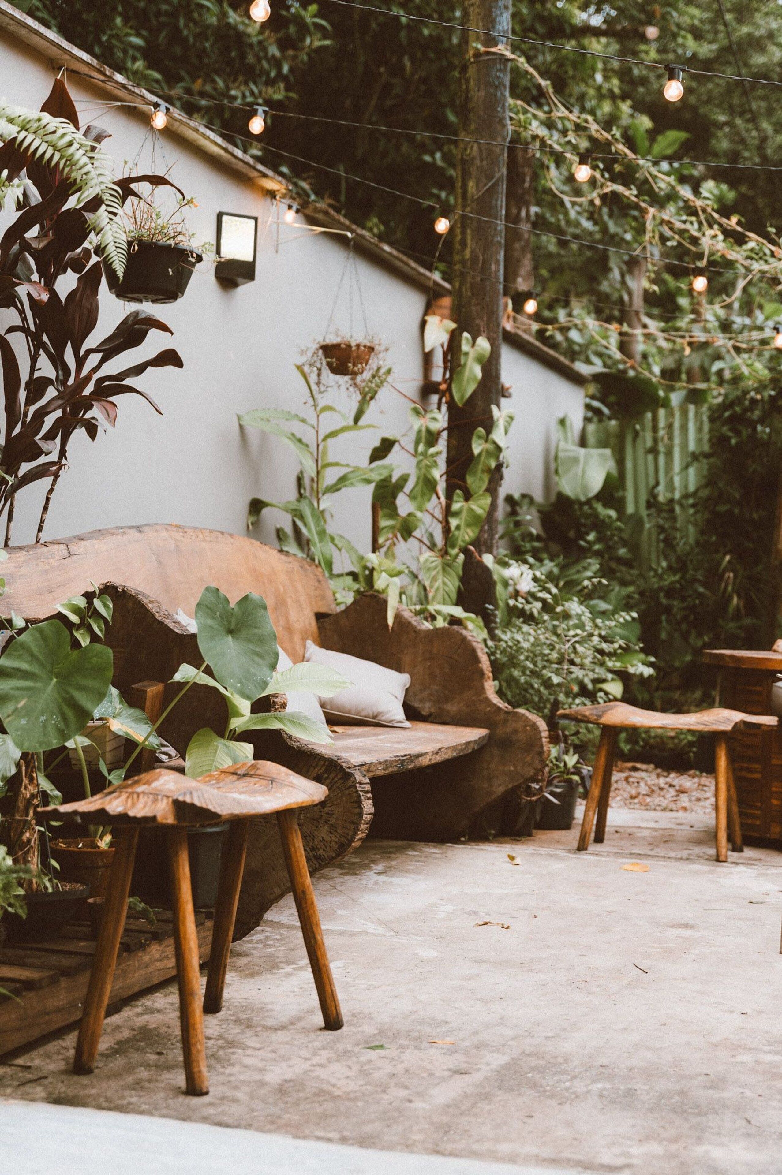 Un espacio de estar al aire libre rústico con muebles de madera y plantas colgantes.
