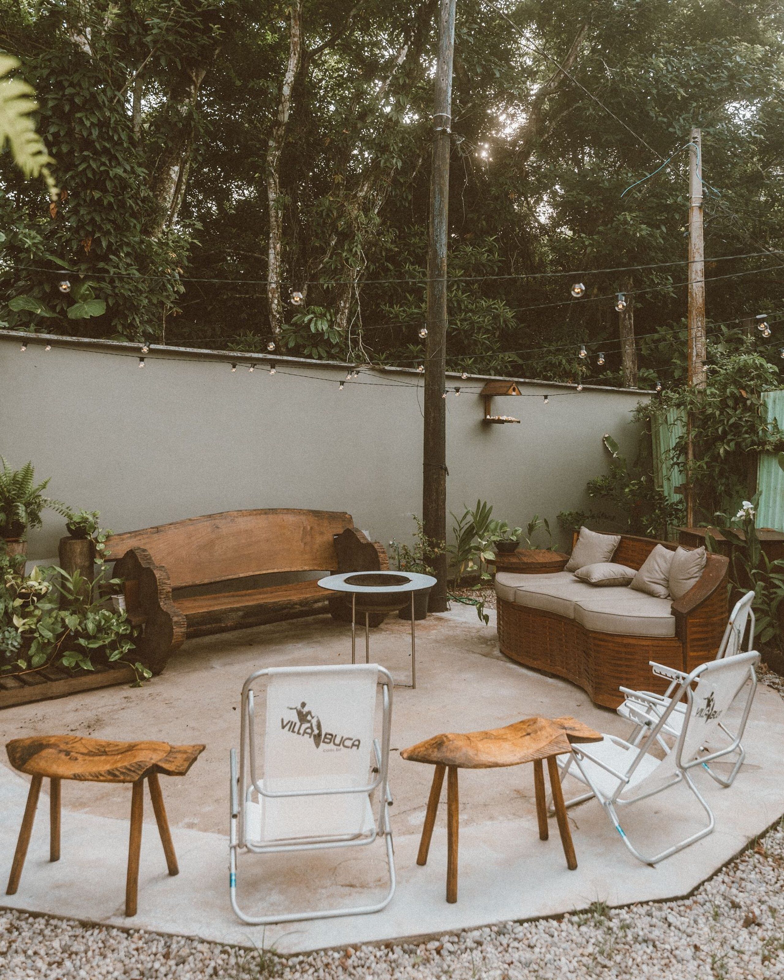 An outdoor patio area with a wooden sofa, a cushioned bench, and a metal chair.