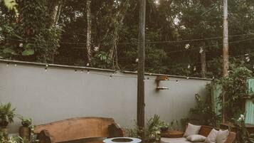 An outdoor patio area with a wooden sofa, a cushioned bench, and a metal chair.