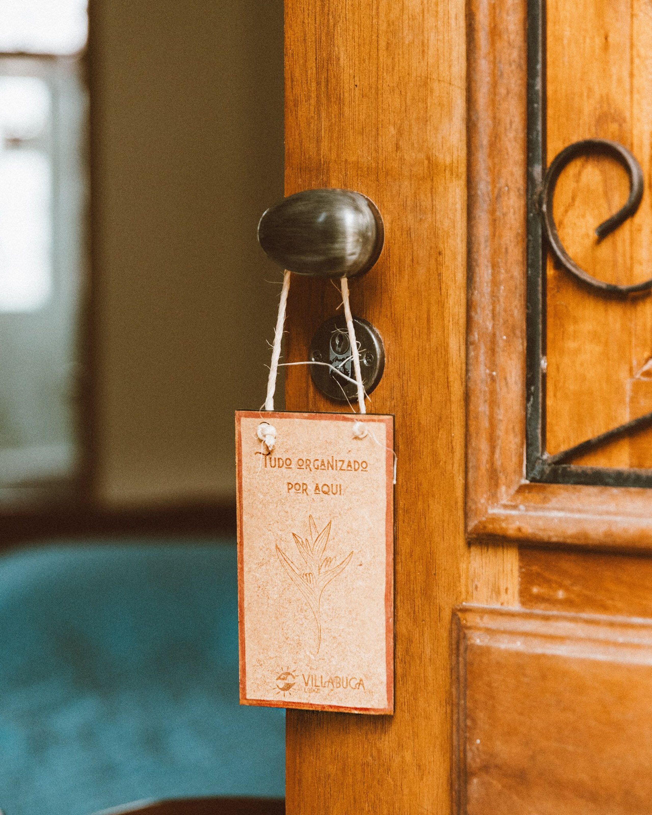 Une porte en bois avec une poignée en métal et une petite pancarte qui y est accrochée.