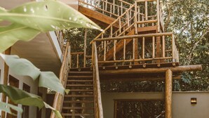Eine Holztreppe führt zu einem Balkon mit einer Hängematte.
