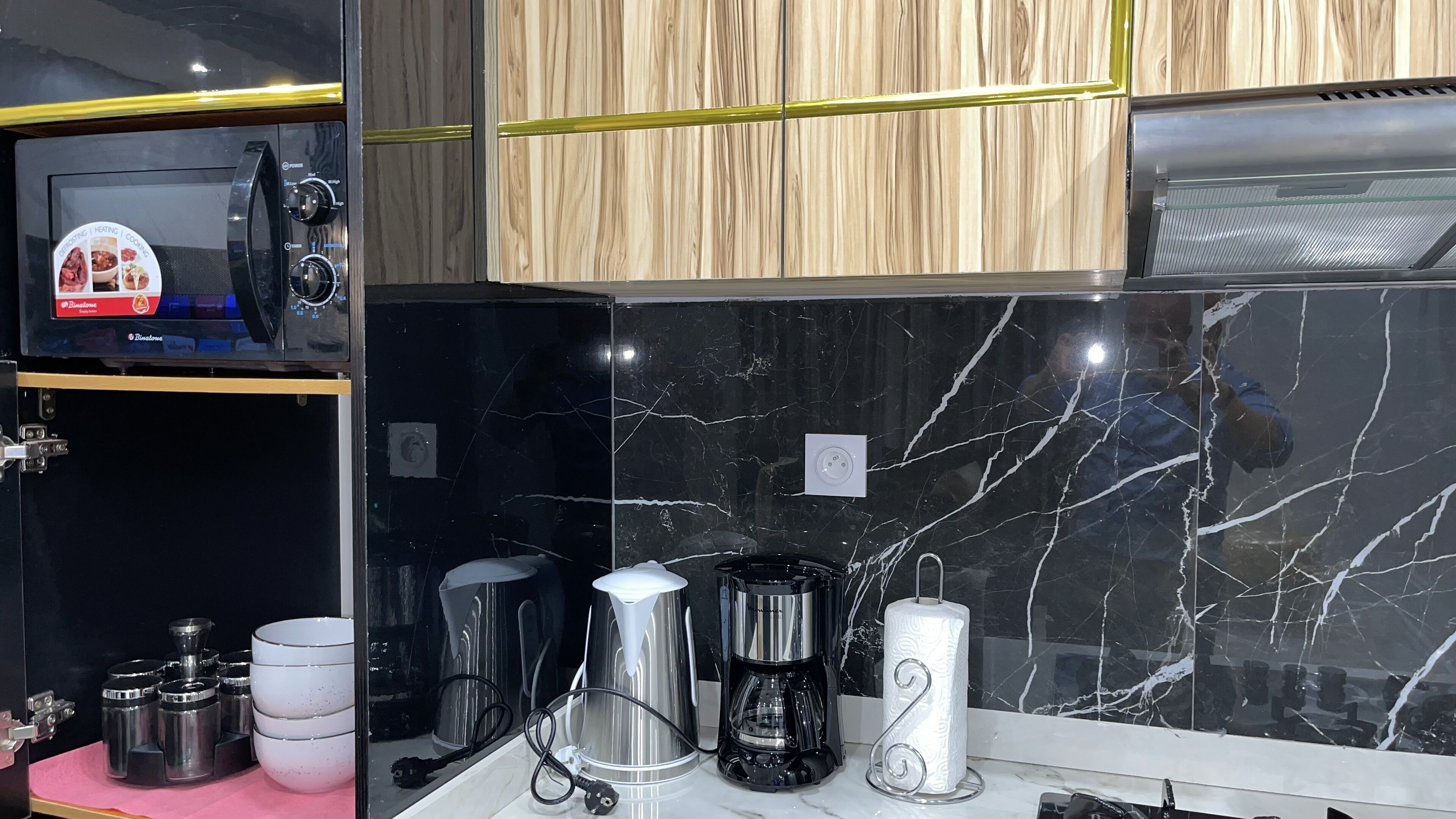 A kitchen with a microwave, coffee maker, and various containers.