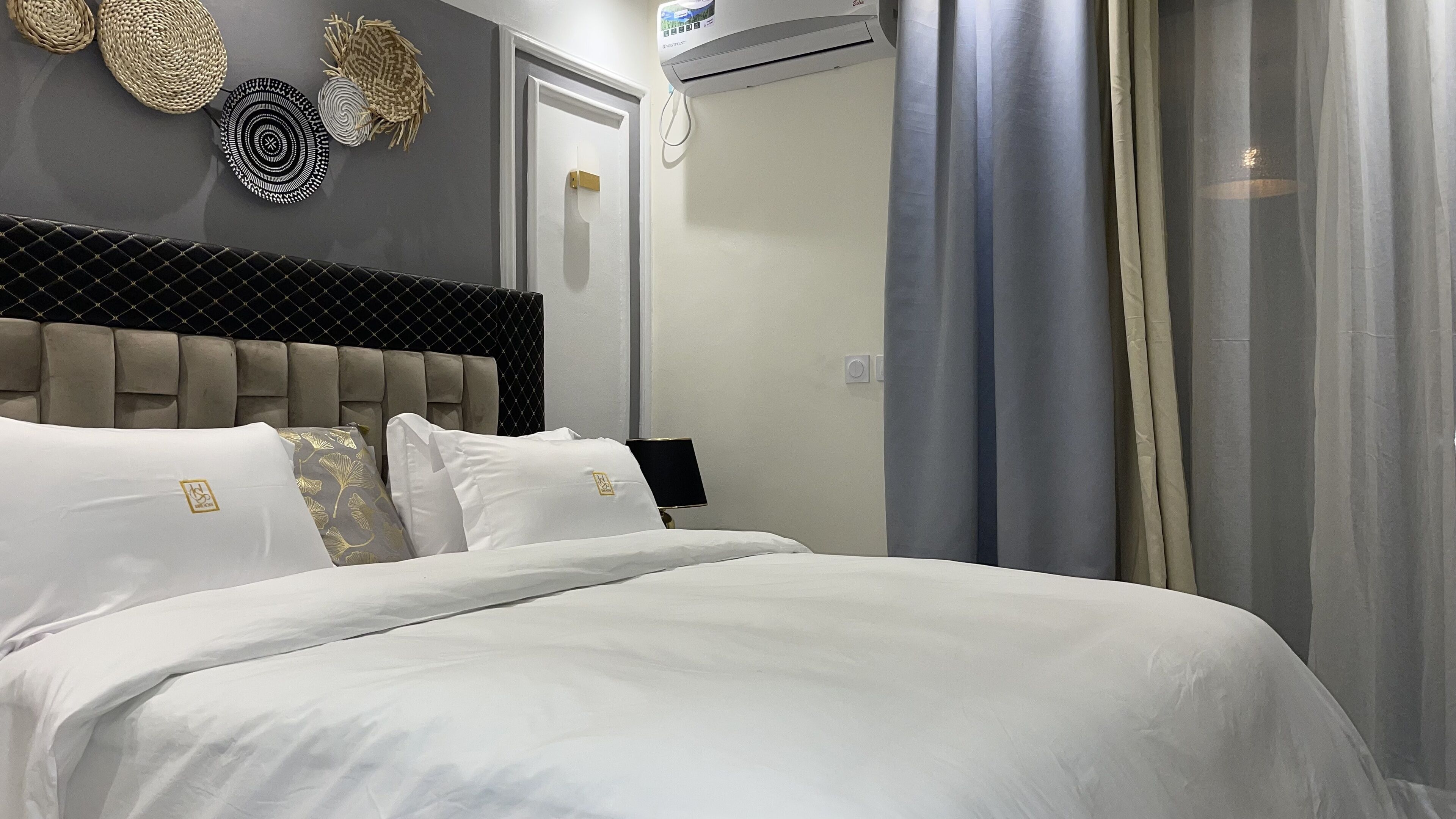 Un lit bien fait, avec du linge de lit blanc et une tête de lit à motifs capitonnés.