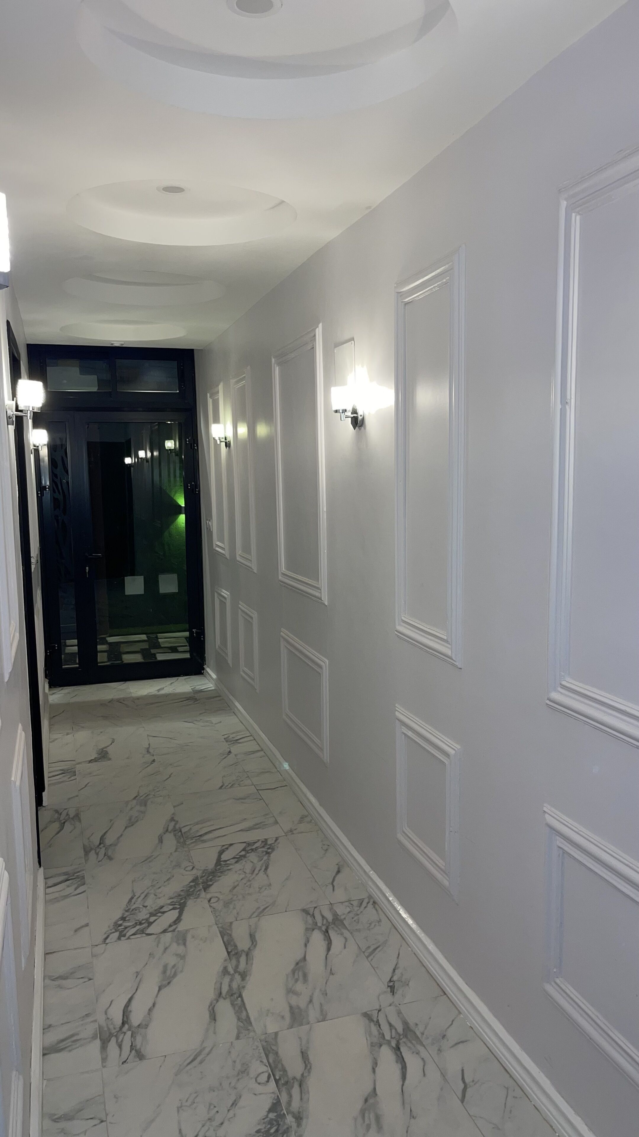 A hallway with marble flooring, white walls, and decorative molding.